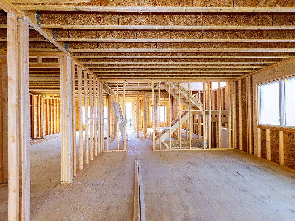 Interior view of wood frame building showing stud walls, joists, staircase, and plywood flooring in Ontario