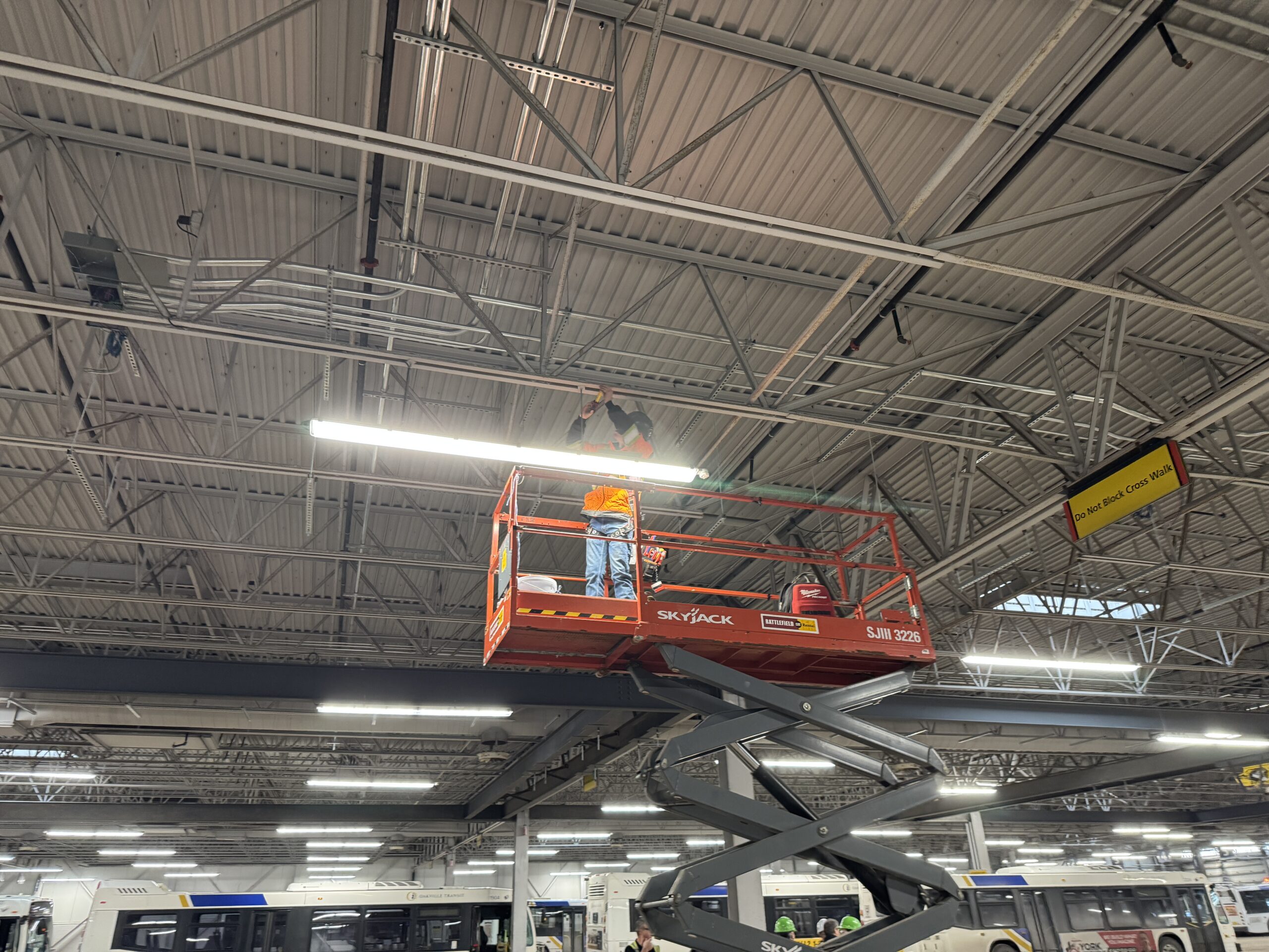 Technicians measuring steel joists during site visit in bus maintenance facility