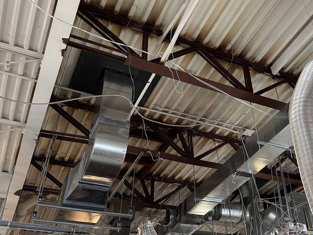 Structural engineer evaluating existing steel roof framing and mechanical equipment for structural modifications in an industrial building